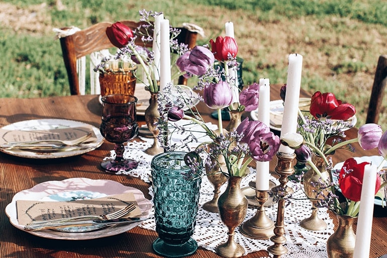 Tischdeko mit Blumen und bunten Gläsern