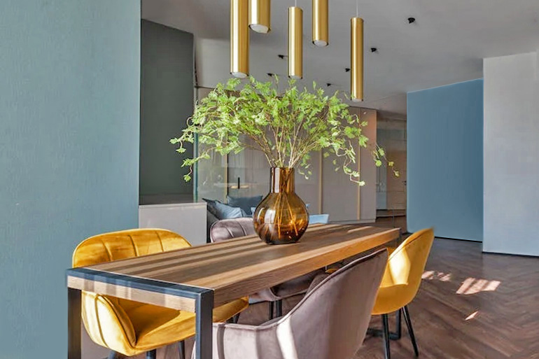 Ein Esszimmer in dem Farbton ,,Wellness Blue" mit einem Massivholztisch und hochwertigen Esszimmerstühlen verbreitet entspannte Stimmung